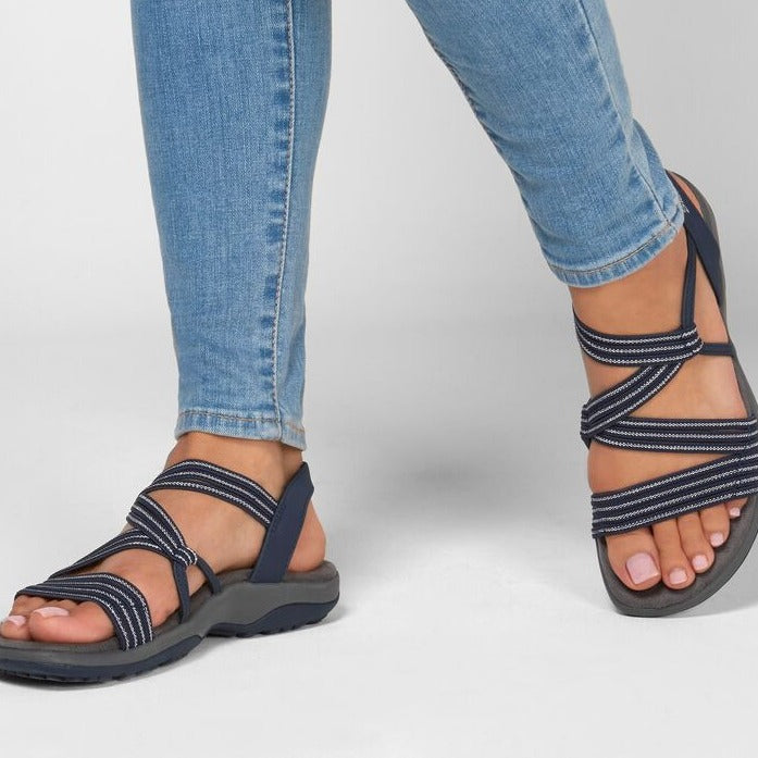 Nahaufnahme einer Frau, die blaue orthopädische Sandalen mit überkreuzten Riemen trägt